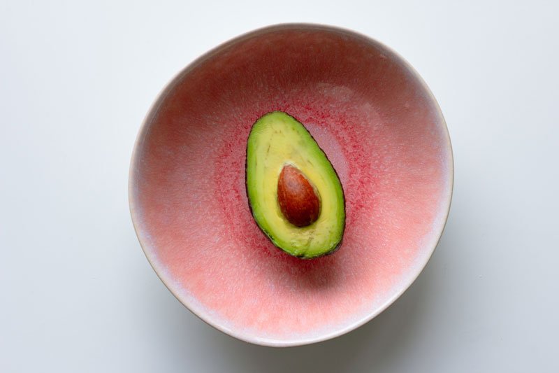 half avocado in a pink bowl